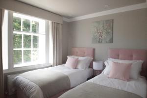 two beds in a room with two windows at 10 Bootham House - luxury city centre apartment with free parking for one car in York