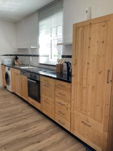 a kitchen with wooden cabinets and a washer and dryer at Alte Gießerei in Ziesendorf