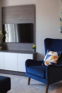 a living room with a blue chair and a television at 10 Bootham House - luxury city centre apartment with free parking for one car in York