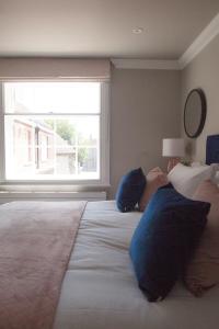 a bedroom with a large bed with blue pillows and a window at 10 Bootham House - luxury city centre apartment with free parking for one car in York