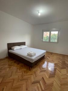 a bedroom with a bed and a wooden floor at Entire spacious apartment with free parking in Podgorica