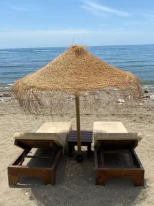 una mesa de picnic con una sombrilla de paja en la playa en Jardines del Mar ,Casa Apolonia, en Marbella