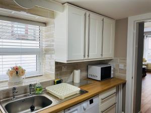 a kitchen with white cabinets and a sink and a microwave at Haven House in Derry Londonderry