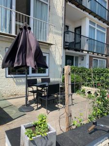 een patio met een parasol en een tafel en stoelen bij El Sol Zandvoort 2 in Zandvoort