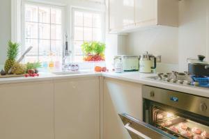 una cucina con armadi bianchi e forno di Discover the Exclusive Charm of Covent Garden at a Luxury Nomads Home a Londra