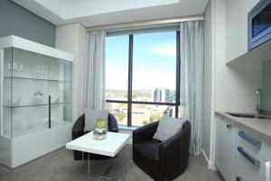 uma sala de estar com uma cadeira, uma mesa e uma janela em Sandton Skye Exclusive Apartment em Joanesburgo