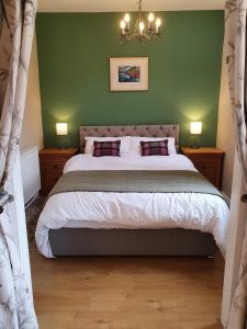 ein Schlafzimmer mit einem großen Bett und einer grünen Wand in der Unterkunft Cosy peaceful one-bedroom cottage in Pitlochry in Pitlochry