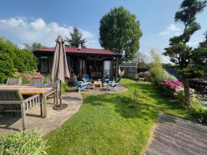 a patio with a table and an umbrella at The Outpost Lakehouse- enjoy our house at Reeuwijkse Plassen - near Gouda in Reeuwijk