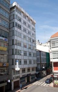 Un edificio grigio alto con un cartello davanti. di Hostal La Provinciana a La Coruña