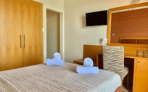 sypialnia z łóżkiem z niebieskimi ręcznikami w obiekcie Hotel Flisvos w Kalamácie