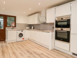 a kitchen with white cabinets and a washer and dryer at Rivendale in Colne