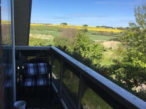 a balcony with a chair and a view of a field at Nationalpark Thy guesthouse in Vestervig