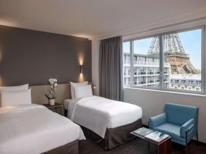 una camera d'albergo con due letti e la torre Eiffel di Pullman Paris Tour Eiffel a Parigi