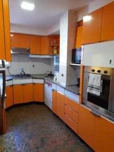 una cocina con armarios naranjas y electrodomésticos de acero inoxidable en Bed & Bike Hostel, en San Lorenzo