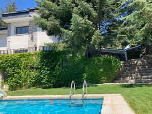 a swimming pool with two metal handles in a yard at Los Cedros, gran chalet con piscina en Navacerrada in Navacerrada