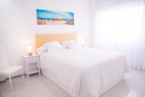 a white bedroom with a white bed and a chair at O Grove Centro con vistas a La Toja parking in O Grove