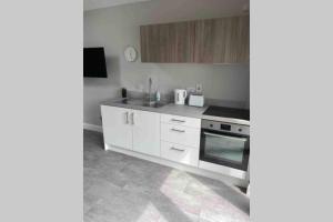 a kitchen with white cabinets and a stove at The Forest Chalet - Stunning Studio Apartment in Ballycastle
