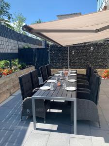 a table and chairs under an umbrella on a patio at Berg Fux - Zwei Ferienhäuser mit je 5 und 6 Schlafzimmern mit eigener Dachterrasse - fantastischem Bergblick - Weber Gas Grill in Sonthofen