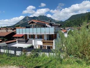 a white building with a mountain in the background at Berg Fux - Zwei Ferienhäuser mit je 5 und 6 Schlafzimmern mit eigener Dachterrasse - fantastischem Bergblick - Weber Gas Grill in Sonthofen