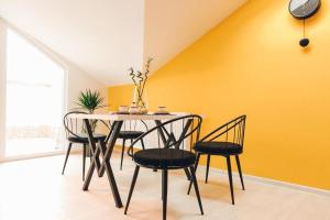 a dining room with a table and chairs against a yellow wall at Studio „Pompei” Brasov in Braşov
