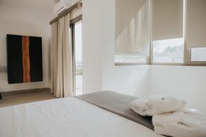 um quarto com uma cama com lençóis brancos e uma janela em elia boutique hotel em Parga