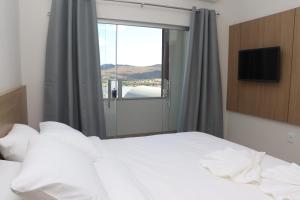 Un dormitorio con una gran cama blanca con ventana. en TS HOTEL, en Porteirinha 29 fotos más