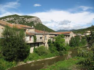 a group of buildings next to a river with a mountain at Le Mazet 1823 in Saint-Hippolyte-du-Fort