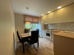 a kitchen with a table with chairs and a vase of flowers at Apartamentai 128 in Panevėžys