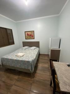 a bedroom with a bed and a refrigerator at Hotel Calema in Capitão Leônidas Marques