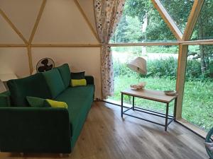 a living room with a green couch and a table at Młyn Hipolit glamping in Nowy Gaj
