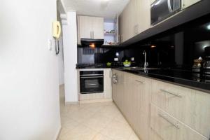 una cocina con armarios blancos y encimeras negras en Apartamento - 3 Dormitorios en el Rodadero ツ en Puerto de Gaira