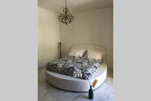 białe łóżko w pokoju z żyrandolem w obiekcie Terrazzo Esclusivo con zona Solarium da 200 mq w mieście Valderice