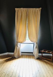 a window with curtains in a room with a wooden floor at B&B 't Kasteel & 't Koetshuys in Veurne