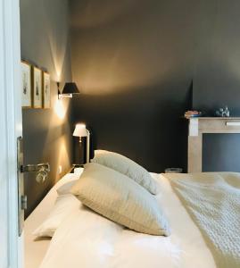 uma cama com lençóis brancos e almofadas num quarto em B&B 't Kasteel & 't Koetshuys em Veurne
