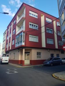 a red building with cars parked in front of it at Piso in Cedeira
