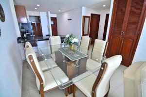 Torres del Lago Apartamentos في كارتاهينا دي اندياس: غرفة طعام مع طاولة زجاجية وكراسي بيضاء