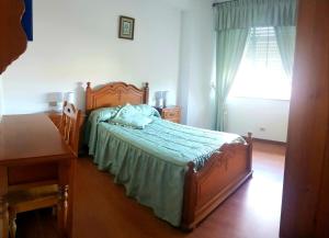 1 dormitorio con cama, mesa y ventana en Piso en Cedeira