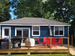 una casa azul con sillas y una mesa en una terraza en Stoneburg Cove Cottages, en Carrying Place