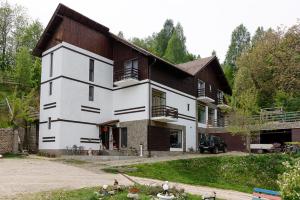 a large white house with a wooden roof at Pensiunea Glasul Pădurii in Braşov