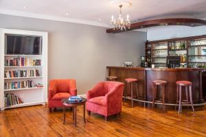 un bar con sillas rojas, una mesa y libros en Willowbrook Country House, en Somerset West