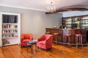 a bar with red chairs and a table and books at Willowbrook Country House in Somerset West