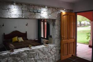 1 dormitorio con 1 cama y pared de piedra en Estancia Santa Leocadia en Bialet Massé