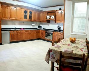 a kitchen with wooden cabinets and a table with a table cloth at Piso in Cedeira