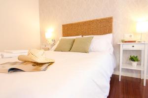 um quarto com uma cama branca com um chapéu em Valente Flat by Serendipia Turismo em Santiago de Compostela