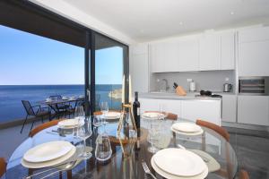 une salle à manger avec une table en verre et une cuisine dans l'établissement New&Luxury Apartment with an Outstanding View - Bombii Blue, à Dubrovnik