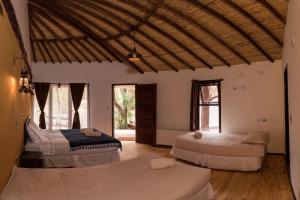 a room with three beds in a room with windows at Lodge Atacama Horse in San Pedro de Atacama