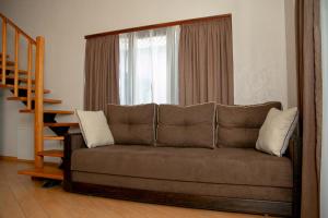 un sofá en una sala de estar con ventana en Oasis family apartments en Sanzhiyka