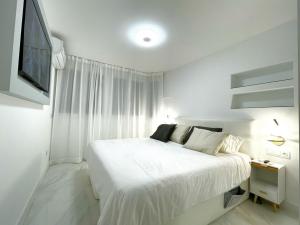 a white bedroom with a bed and a tv at Apartamento IMPERIO 2 - Marbella centro in Marbella