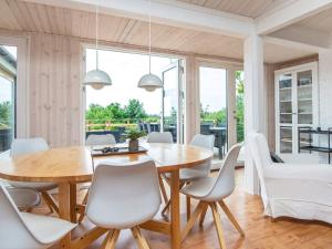 エーベルトフトにある6 person holiday home in Ebeltoftのダイニングルーム(木製テーブル、白い椅子付)