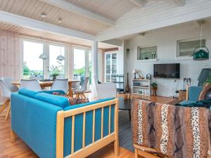 エーベルトフトにある6 person holiday home in Ebeltoftのリビングルーム(青いソファ、白い椅子付)